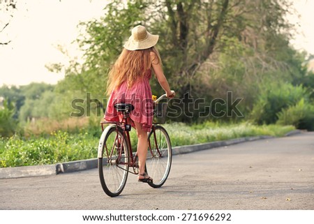 young woman in a dress and hat rides a bike in a summer park. Active people. Outdoors