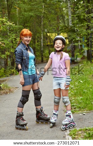 sports mother and daughter in a helmet. family on the skates. two people rollerblade. rollerskating outdoor