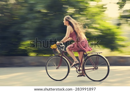 motion blur. young woman in a dress rides a bike in a summer park. Active people. Outdoors