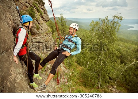 young couple in love climbers. man and woman hanging on a rock on the ropes. climbing, extreme sport