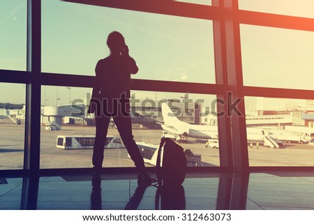 businesswoman at the airport. silhouette of a girl with mobile phone and backpack. business and travel