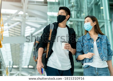 young Asian male and female couple tourists drag luggages walking through the hallway after arrival ,two asian people traveller wearing facial face mask virus protection safety travel ideas concept