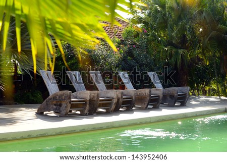 pool chairs on deck at a hotel in tropics with palms