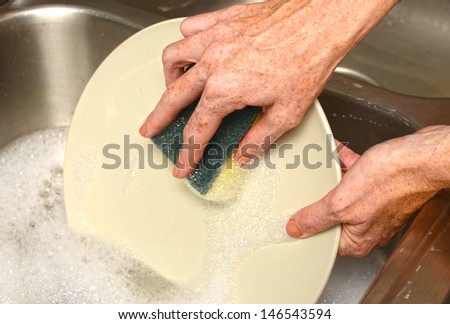 cleaning plate in soapy water while doing dishes