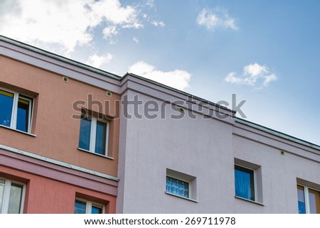Close up of top part of block of flats building with blue sky. Architecture abstract.