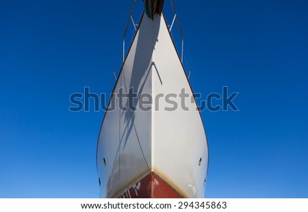 Close up of front side of big ship in port. Ship trunk on blue sky background