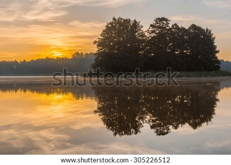 Beautiful sunrise over misty lake. Lake in Warmia and Mazury lake district in Poland. Summer calm weather