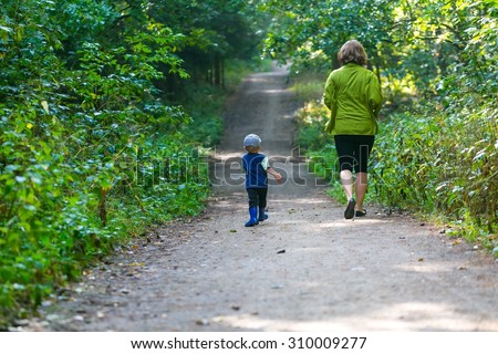 Little boy running and playing in forest at summer. Beautiful summer forest landscape with one small boy.