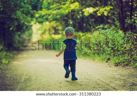Vintage photo of little boy running and playing in forest at summer. Beautiful summer forest landscape with one small boy.