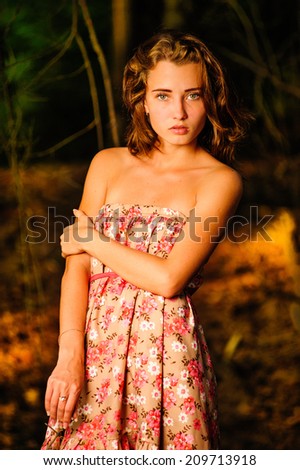 Frightened young woman standing in the woods, on a dark red and Orange, background