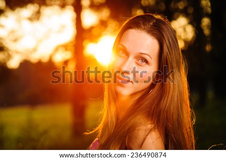 portrait of a beautiful young woman in the forest at sunset