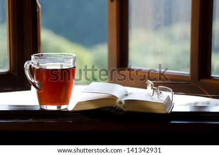 ?up of tea, chamomile flower and an open book on the window. The concept of reading.