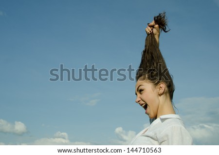 Beautiful girl  pulls his hair on sky background.