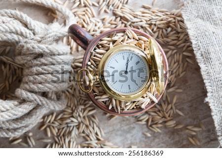 harvest time, gold pocket watch and oat grain on the table