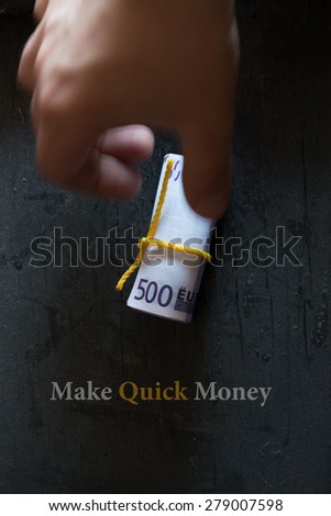 Make Quick Money. Roll of money on a dark table hand and an inscription.