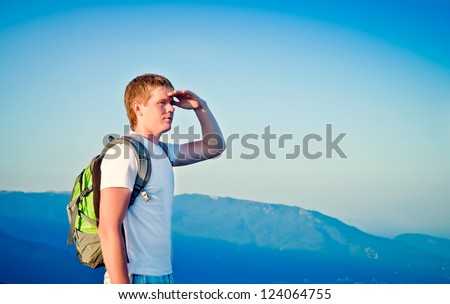 young guy is in the mountains and looks into the distance