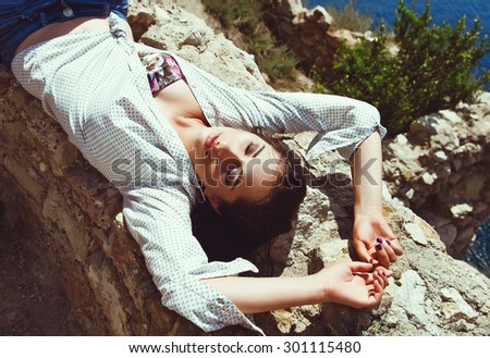 Young fashionable woman Leger on rocks top view
