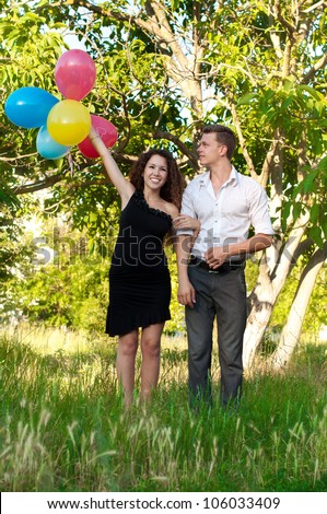 Young beautiful couple in love holding bunch of balloons