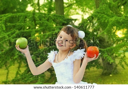 cute girl with green and red apples in the park