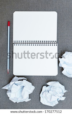crumpled up papers with a sheet of blank paper and pencil