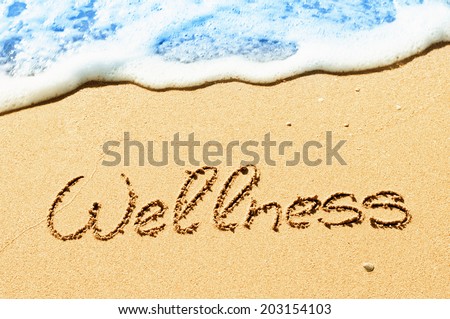 Wellness concept written on sand