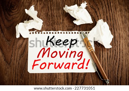 Keep Moving Forward written on a paper on wood table