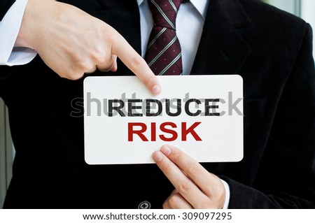 Reduce Risk Concept. Man holding a card with a message text written on it