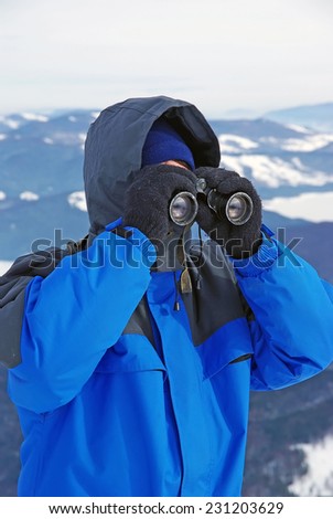 Tourist on mountain looking through binocular.