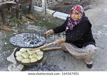 ANKARA - OCTOBER 24, 2013: Traditional Turkish country woman cooking pasties onto the pan at their Village which name is Cubuk in Ankara, Turkey.