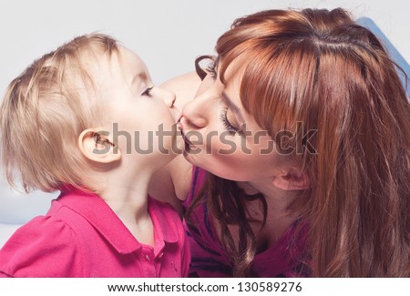 Portrait of a little girl kissing a mum on the lips