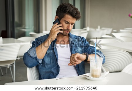 Young handsome man calling and checking the time