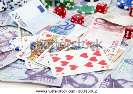 Poker hands - cards have focus with poker chips and money in background.