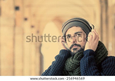 young stylish bearded man listening to music in a mediterranean city in instagram tones