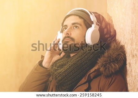 a young man listens to music in an urban image of modern life warm tones style toned