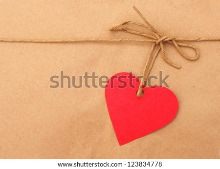 String tied in a bow with red heart over brown paper packaging.