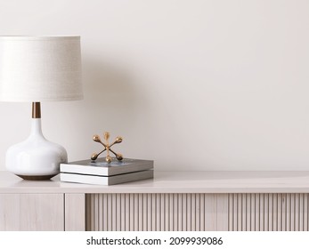 3D close up, a stylish contemporary white table lamp with gold lining and linen cloth lampshade stand next to some books on a minimal wooden sideboard. Empty blank beige wall in background. Mock up. 