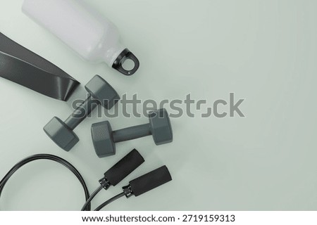 3D flat lay of dark grey dumbbells, jump rope, water bottle, and exercise band on a light sage green background. Professional fitness equipment composition for healthy lifestyle content.