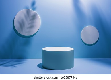 3D Illustration. Creative Layout Made Of Blue Studio Background For Product Placement Or Display With A Circular Plinth In Front Of Two Blank Round Wall Plaques With The Shadows Of Palm Tree Fronds.