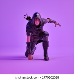 3d Illustration Of Video Game Character Posing Heroically In Studio With Purple Background. Render Of Female Archer With Hood And Arrows Hanging On Her Back.