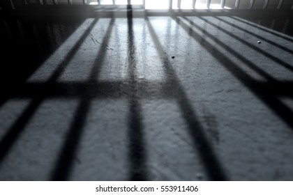 A 3D Render Of A Closeup Of View Of A Jail Cells Iron Bars With An Open Door Casting Shadows On The Prison Floor With Copy Space