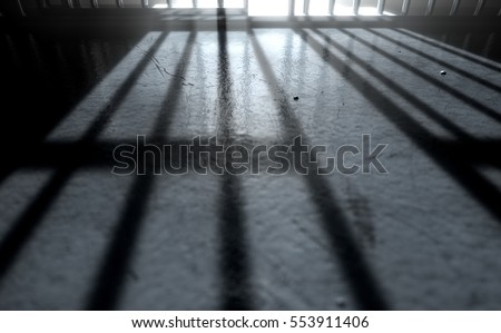 A 3D render of a closeup of view of a jail cells iron bars with an open door casting shadows on the prison floor with copy space