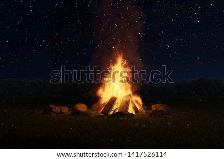 Large campfire with sparks and lots of particles in front of snow-covered pines and a moonlit sky.