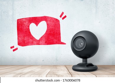 3d Rendering Of Black Web Camera Standing On Wooden Desk Near Grungy Gray Wall With Hand-drawn Red 'Like' Icon. Live Streaming. Popularity On The Internet. Viral Videos.