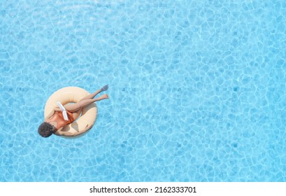 3D rendering drone view of anonymous African American female tourist sitting in swim tube in outdoor pool and reading book - Powered by Shutterstock