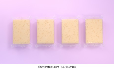 3d rendering of four cheese bricks in transparent plastic wrap. Closed. Square shape. Realistic products packaging mockup with soft shadows. Stands on bright pink background. Top view