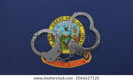 3D rendering of a half opened steel handcuff in center on top of the US state flag of Idaho