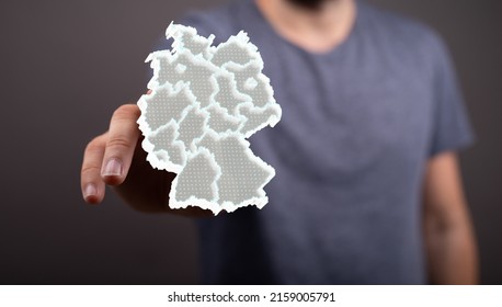 A 3d rendering of the map of Germany with outlined land border and lines and a man pointing it