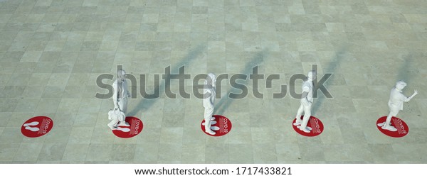 3D rendering of people standing in a queue\
with social distancing floor\
markers