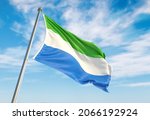 3d rendering Sierra Leone flag waving in the wind on flagpole. Perspective wiev Sierra Leone flag waving a blue cloudy sky