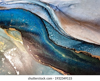 Abstract blue-green background with gold, beautiful smudges and stains made with alcohol ink and metallic pigment. Fragment of art with turquoise texture resembles watercolor or aquarelle painting.